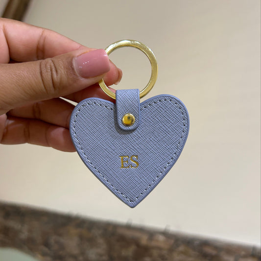 Heart-shaped keychain held by a hand with a neutral background